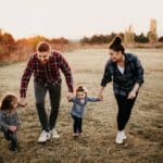 Familia en el parque feliz y protegida con una poliza de salud sura