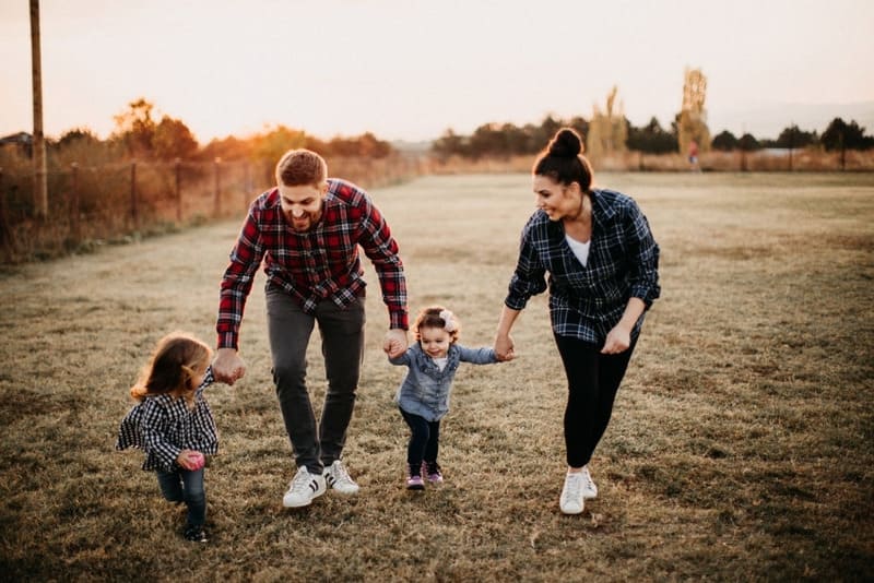 Familia en el parque feliz y protegida con una poliza de salud sura